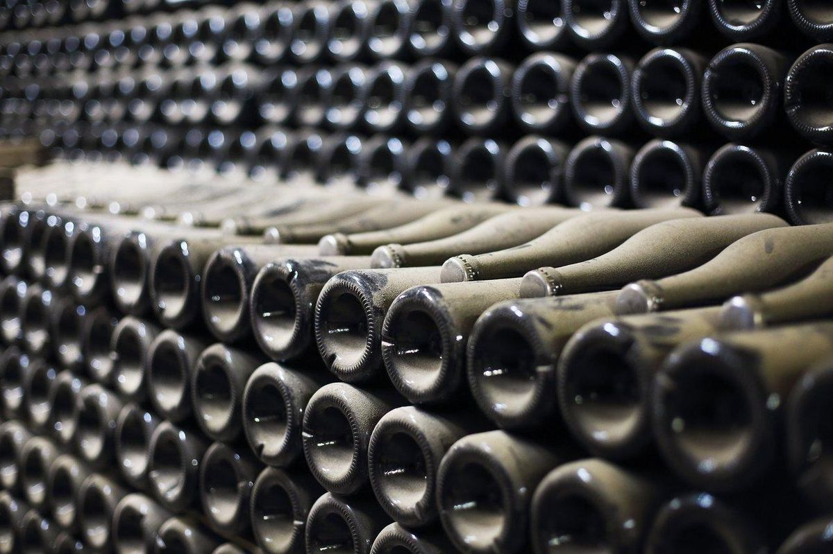 Rangée de bouteilles de vin entreposées horizontalement dans une cave sombre, idéale pour leur conservation en 2025.