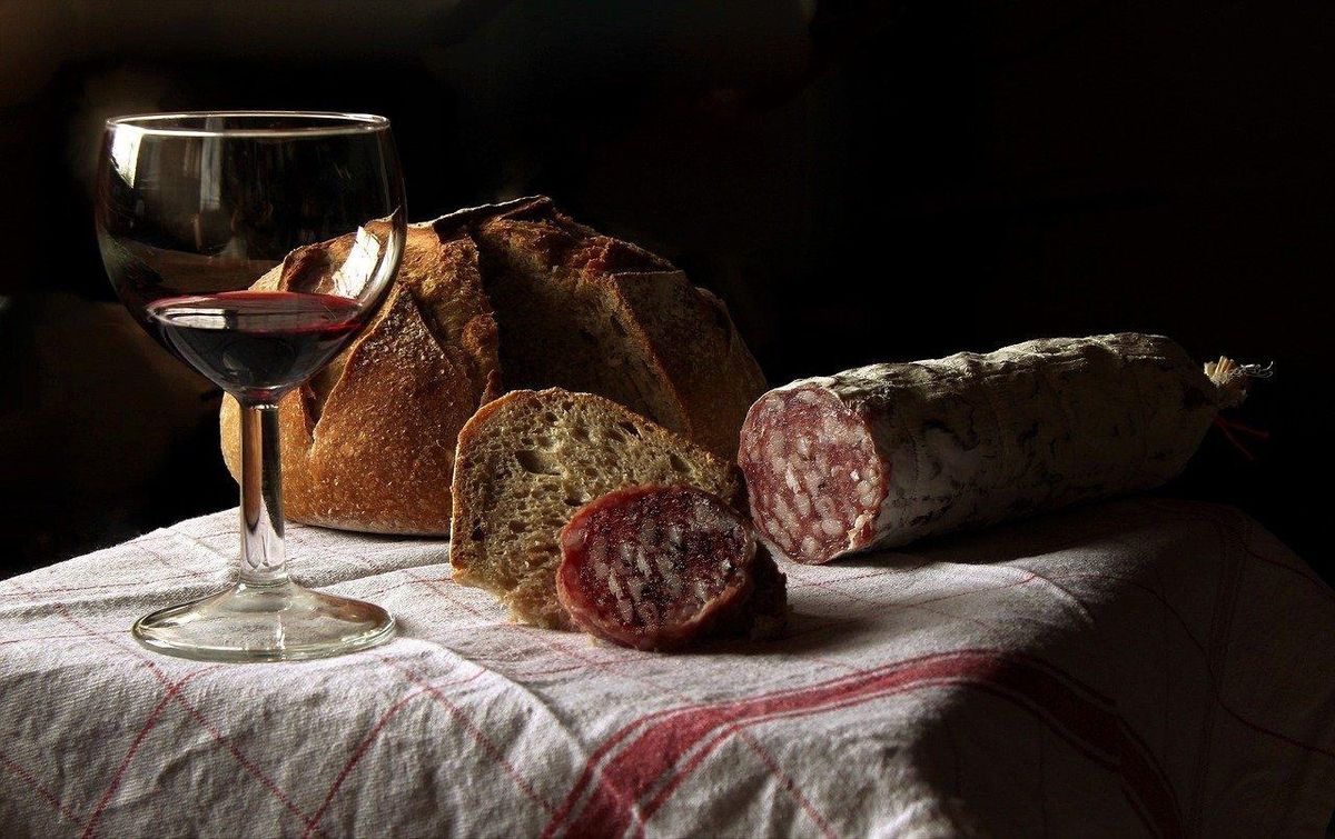 Un verre de vin, pain et saucisson : parfaits pour goûter ses bouteilles bien conservées.
